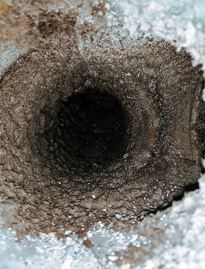 Inuti ett smutsigt ventilationsrör innan ventilationsrengöring, visar att ventilationssystemet behöver rengöras och underhållas för att säkerställa bra inomhusluft.